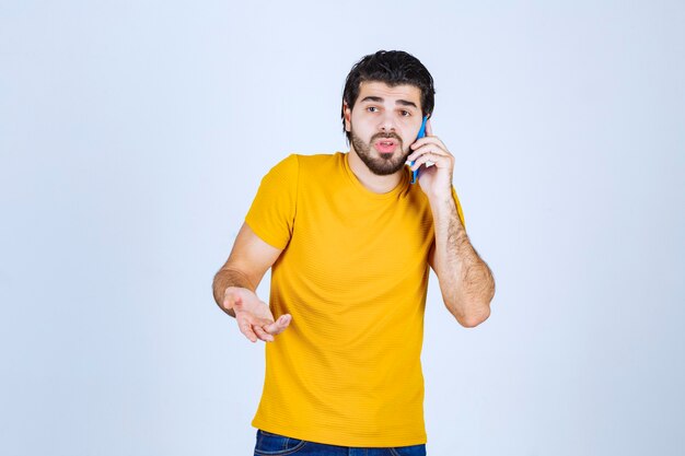 Man in yellow shirt talking to the phone.