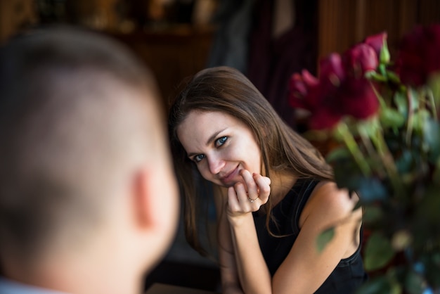 Man and young cheerful woman with hand on chin near flowers 