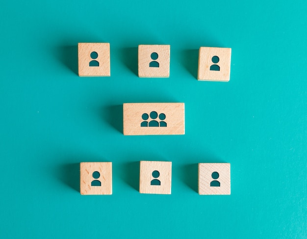 Free photo management structure concept with people icons on wooden blocks on turquoise table flat lay.