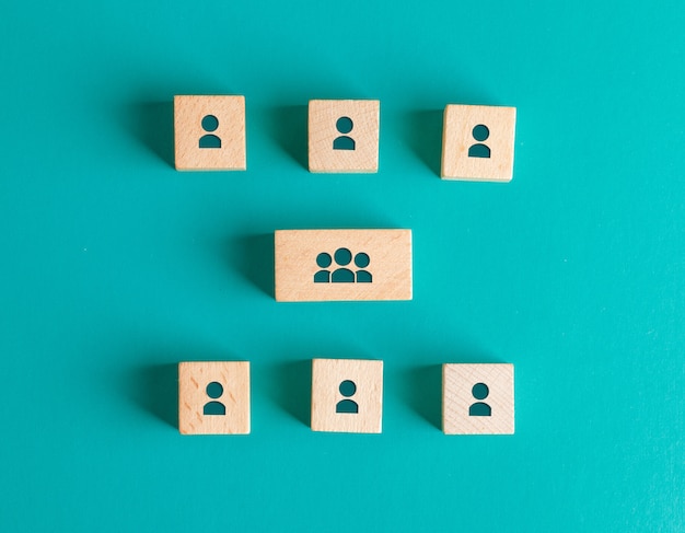 Management structure concept with people icons on wooden blocks on turquoise table flat lay.