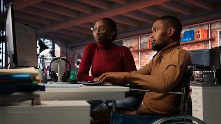 Free Photo manager coming to inclusive startup employee in wheelchair to offer help