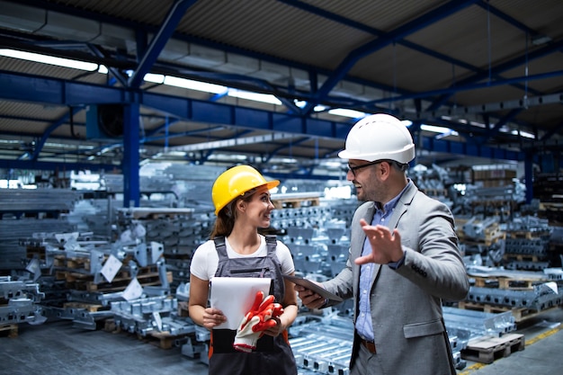 Manager che indossa elmetto protettivo e lavoratore industriale discutendo sulla produzione nella fabbrica di metalli