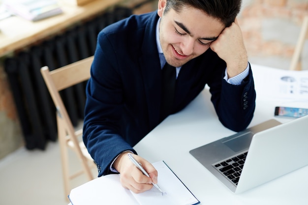 Manager writing on diary notebook