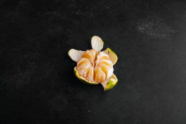 Mandarin orange with green peeled skin. 