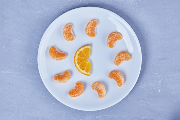 Мандарин и апельсины в белой тарелке.
