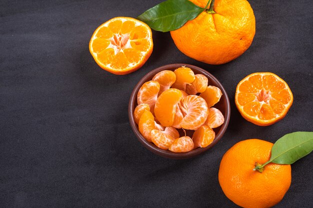 mandarin slices in ceramic bowl on black surface