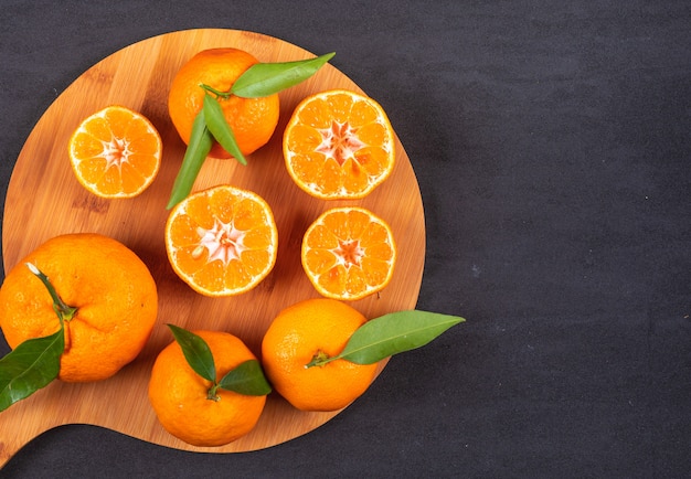 Mandarins top view on wood cutting board on black stone surface