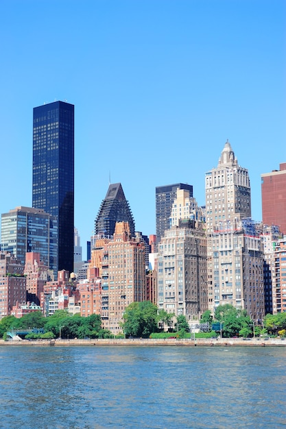 ニューヨーク市の都市の高層ビルと青い空とイースト川の上のマンハッタンミッドタウンのスカイラインのパノラマ
