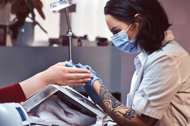 The manicurist does the procedure to trim and remove cuticles in the beauty salon