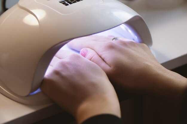 Маникюрша делает дизайн ногтей гель для клиента, крупным планом.