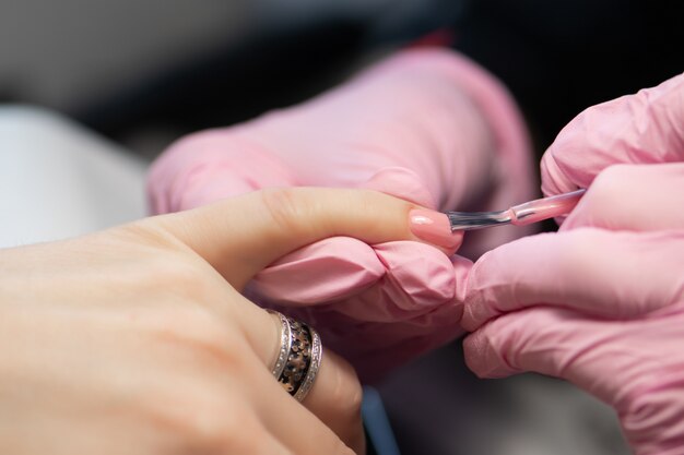 manicurist doing gel nail design for client, close up.