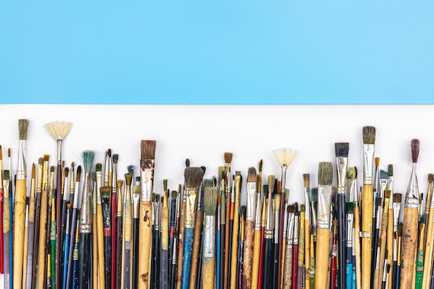 Many brushes for painting on a colored background top view