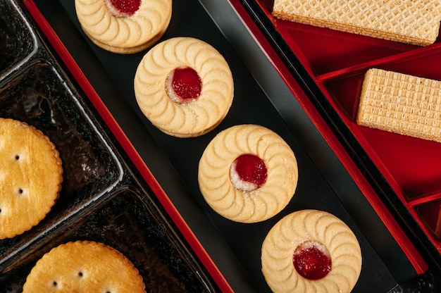 Many cookies are beautifully arranged in a plate and then placed on a wooden table.