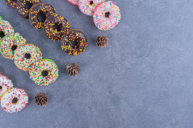 Many of delicious donuts with pinecones on a gray surface