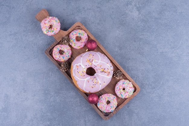 Many of delicious donuts with pinecones on a wooden board