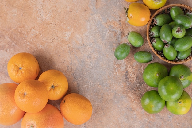 Many of feijoa, tangerine and oranges on marble.