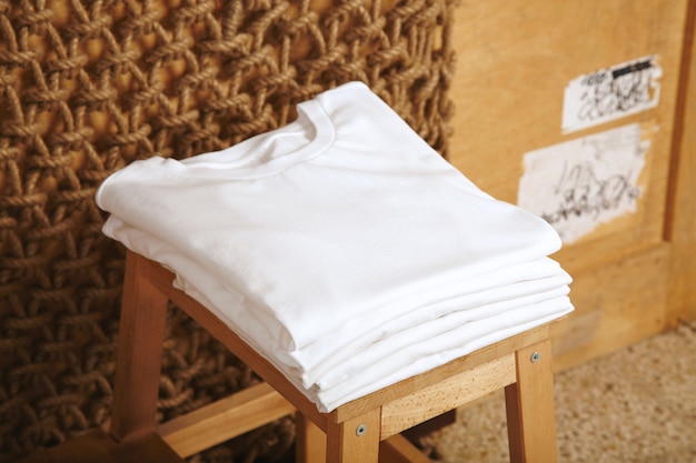 Many folded white basic cotton t-shirts presented in rustic interior