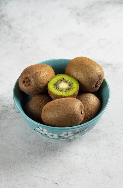 Many of fresh kiwi fruits on blue bowl.