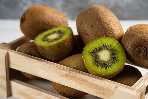 Many of fresh kiwi fruits on wooden basket.