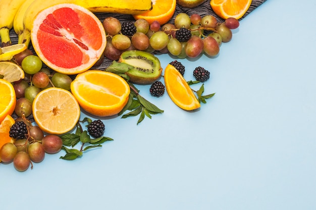 Many fresh organic fruits on blue background