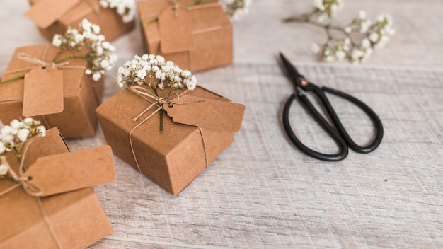 Many gift boxes tied with string and baby's-breath flowers and scissor on wooden backdrop