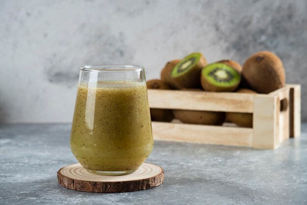 Many of kiwi fruits in a wooden basket with a glass cup of juice. 