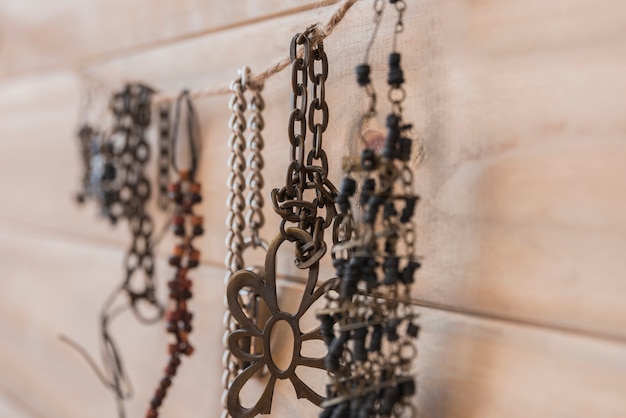 Many metallic bracelets hanging on string against wooden wall