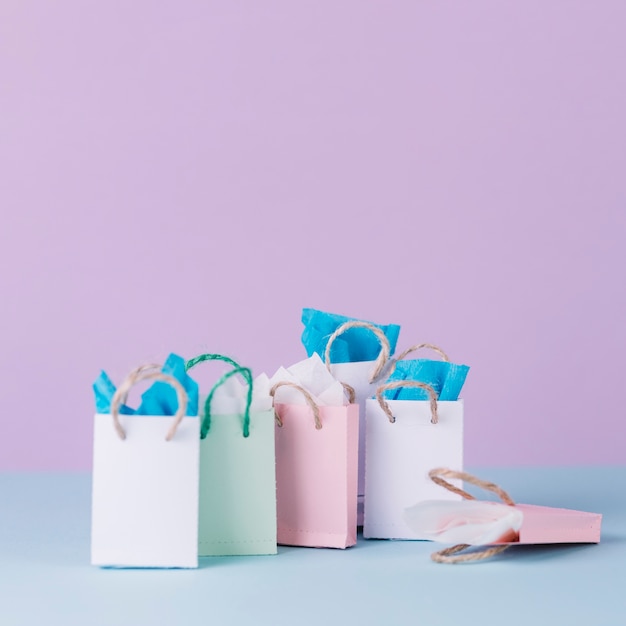 Многие разноцветные сумки для покупок перед розовым фоном