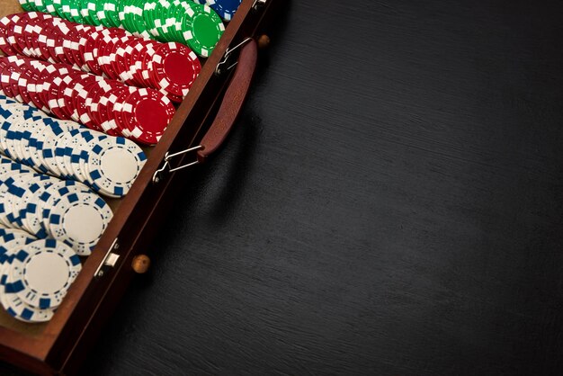 黒​の​背景​に​分離された​スーツケース​の​多く​の​ポーカー​チップ​。​ポーカー