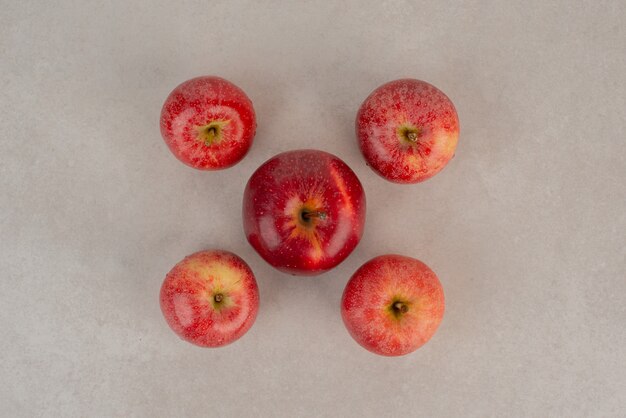 Many of red apples on white table.