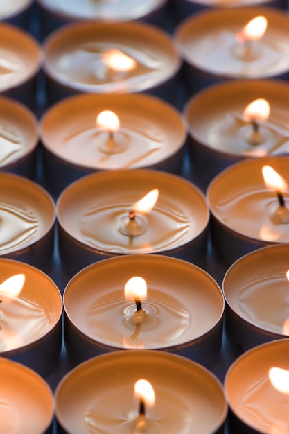 Many small roundness burning candles, close up.