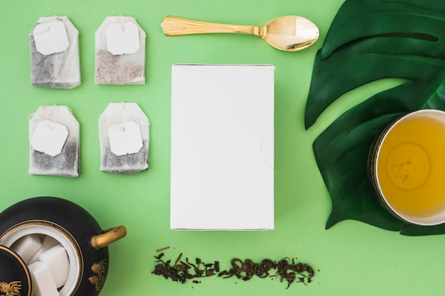 Free photo many tea bag with sugar cubes and box on green background