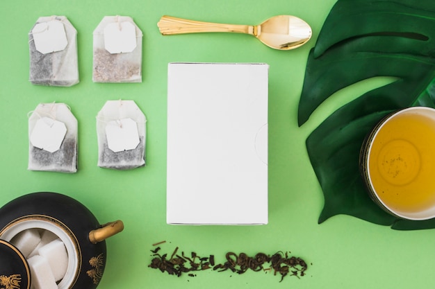 Many tea bag with sugar cubes and box on green background