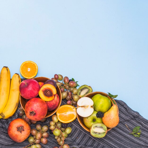 Many tropical fruits on stripes textile against blue background