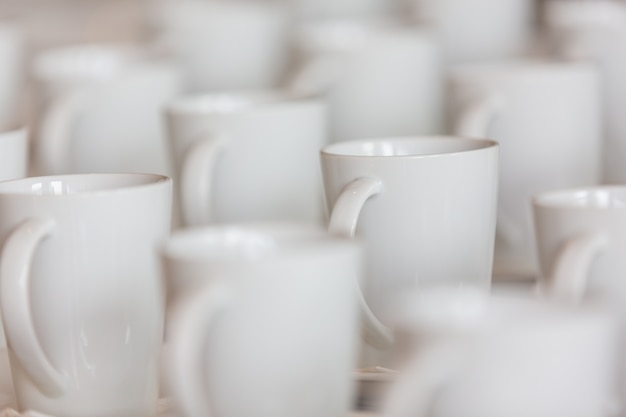 Many white coffee mugs are placed on the table.