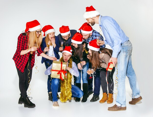 Many young women and men drinking at christmas party on white studio