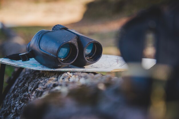 Map and binoculars on a fallen log