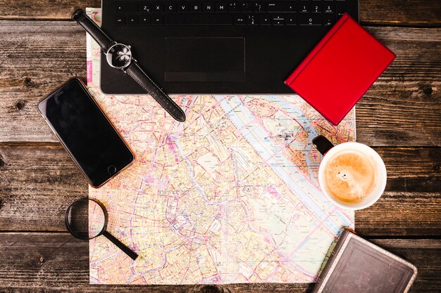 Map, coffee, electronic equipment and accessories on wooden table