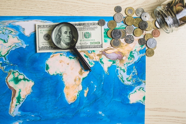 Бесплатное фото Карта мира с деньгами и увеличительным стеклом