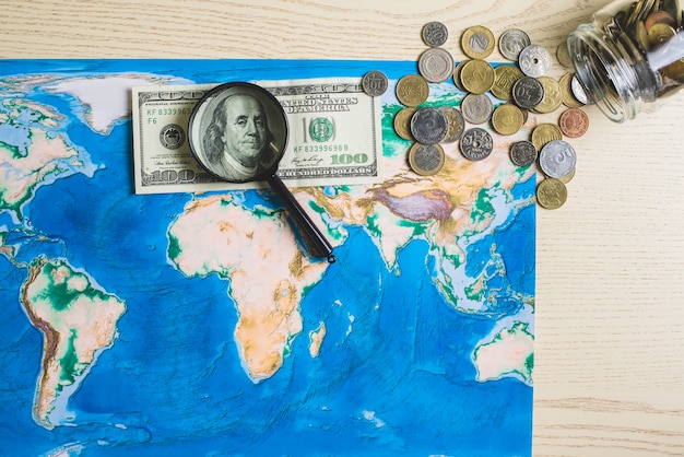 お金と虫眼鏡を持つ世界の地図