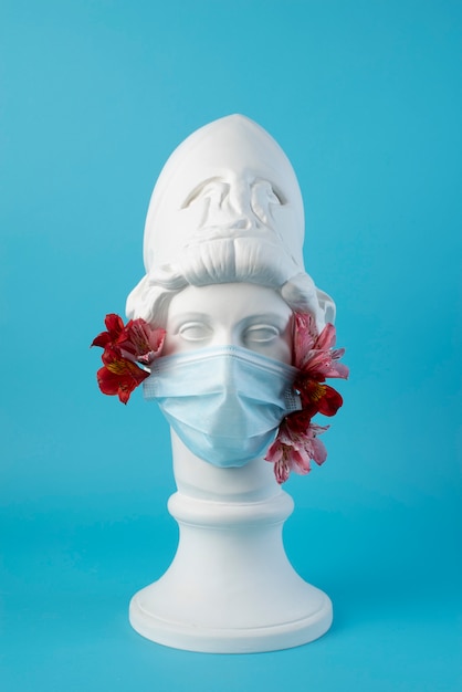 Marble sculpture of historical figure with medical mask and flowers