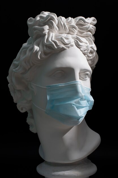 Marble sculpture of historical figure with medical mask