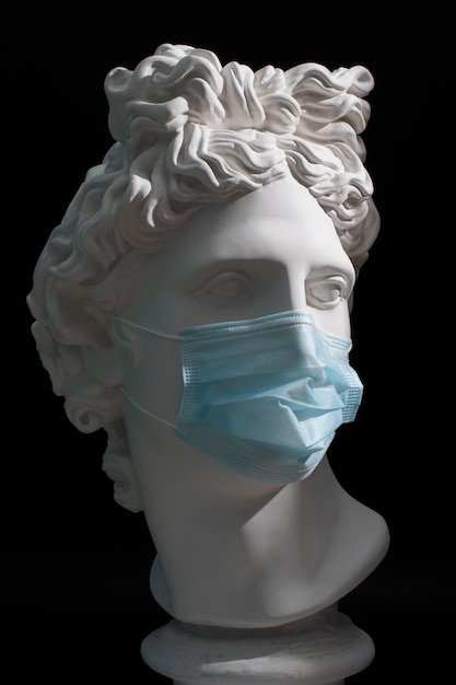 Marble sculpture of historical figure with medical mask