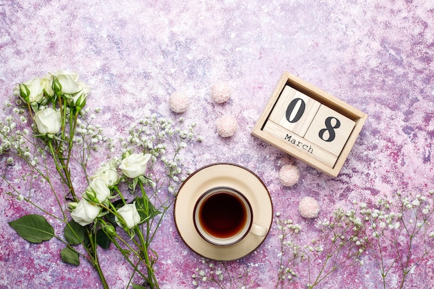 March 8 Women's Day card with white flowers,sweets and a cup of tea .