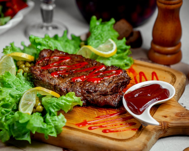 Marinated beef steak served with ketchup and lemon