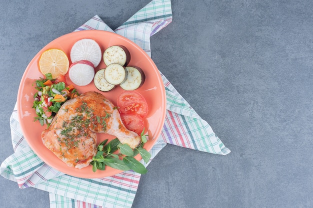 Маринованная курица и нарезанные овощи на оранжевой тарелке.