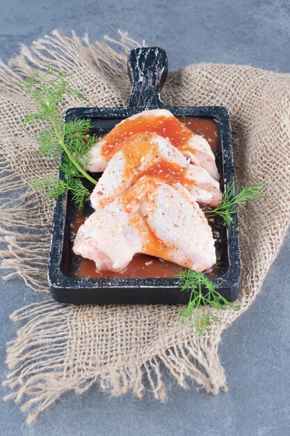 Marinated chicken wings with sauce on black board.