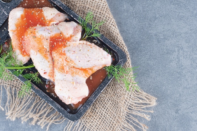 Marinated chicken wings with sauce on black board.