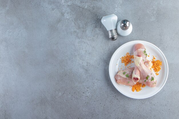 Маринованная свежая голень на тарелке рядом с солью, на мраморном фоне.