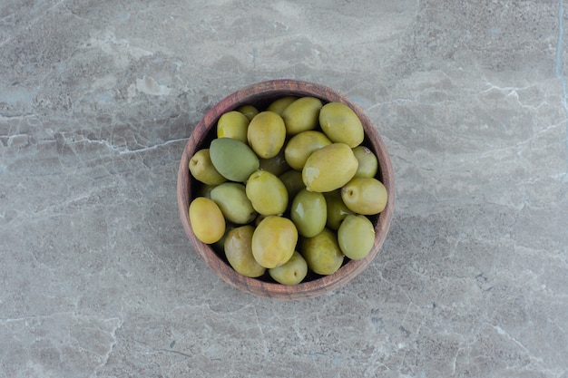 Маринованные зеленые оливки. куча зеленых оливок в деревянной миске.